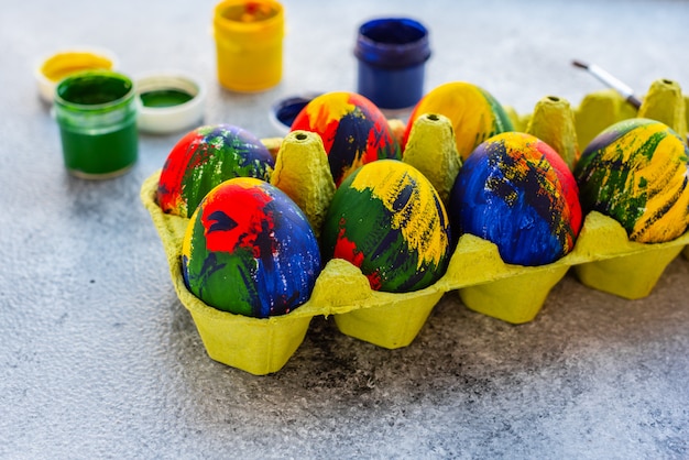 Photo oeufs multicolores de pâques, peintures et pinceaux sur une table. préparation pour des vacances