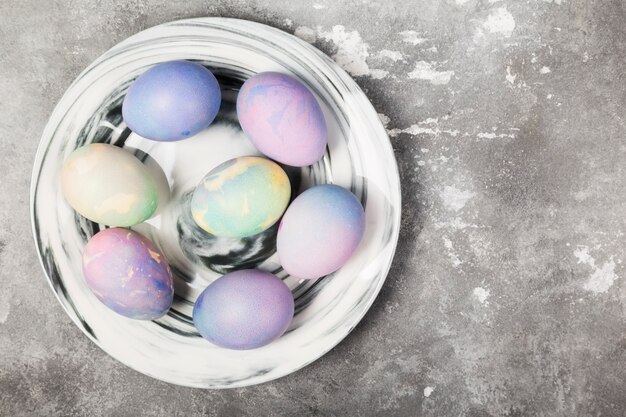 Oeufs multicolores pour Pâques en plaque de marbre sur fond gris. Vue de dessus, espace copie. Contexte alimentaire