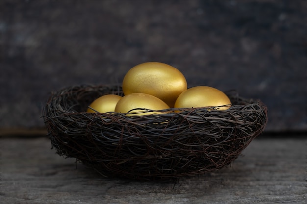 Photo oeufs d'or dans un nid sur la vieille table en bois
