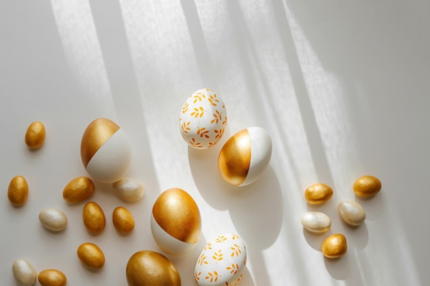 Photo oeufs d'or de pâques et bonbons sur fond blanc concept de vacances carte de joyeuses pâques