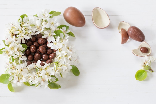 Oeufs de Pâques au chocolat avec des fleurs de printemps sur fond de bois