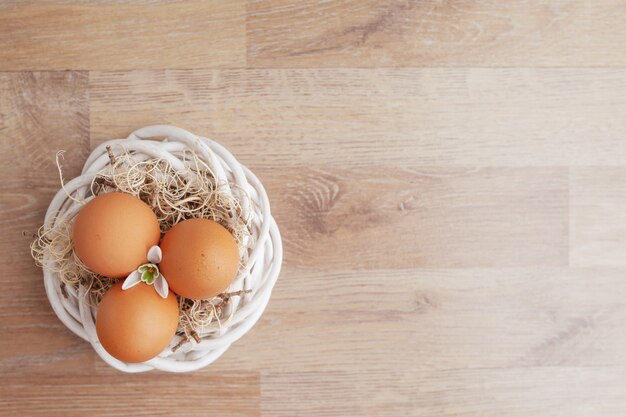 Oeufs de Pâques au nid sur une table rustique en bois, fond de vacances pour votre décoration. Concept de vacances de printemps et de Pâques avec espace de copie.