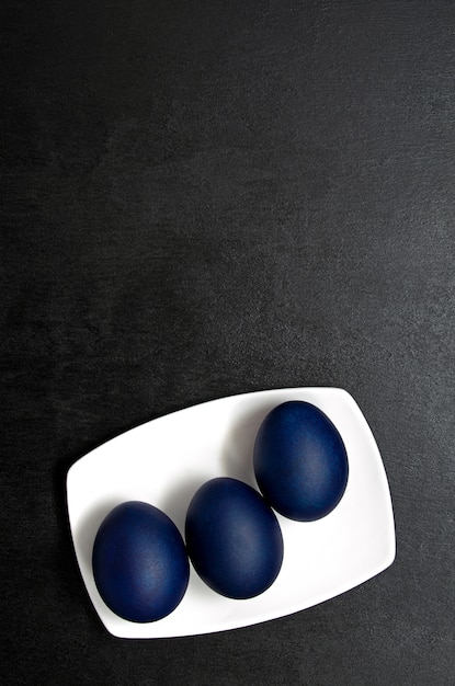 Oeufs de Pâques bleu classique tendance moderne sur une plaque blanche sur fond noir