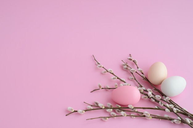 Oeufs de Pâques avec bouquet de saules sur table rose Brindilles de saule et oeufs colorés sur fond rose