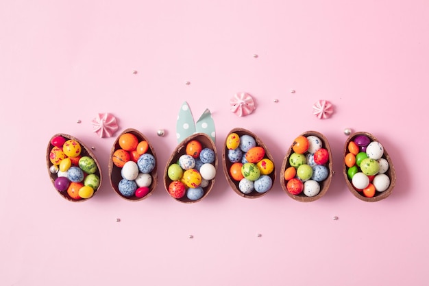 Oeufs de pâques en chocolat et décor plat pour les enfants concept d'oeufs de chasse de pâques sur fond rose Bonbons en forme d'oeuf