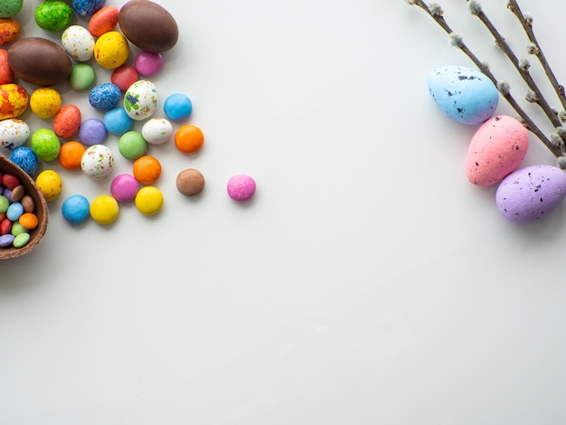 Des œufs de Pâques colorés et au chocolat avec du dragée sucré sur fond blanc