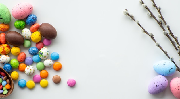 Oeufs de pâques colorés et chocolat avec dragée sucrée sur fond blanc