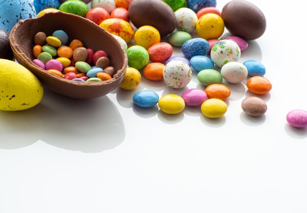 Oeufs de pâques colorés et chocolat avec dragée sucrée sur fond blanc