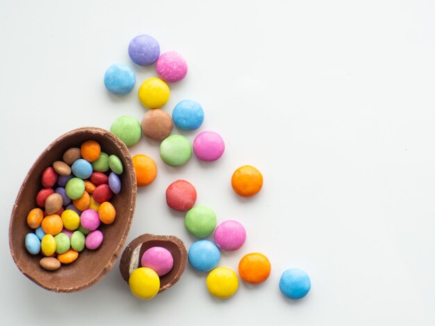 Oeufs de pâques colorés et chocolat avec dragée sucrée sur fond blanc