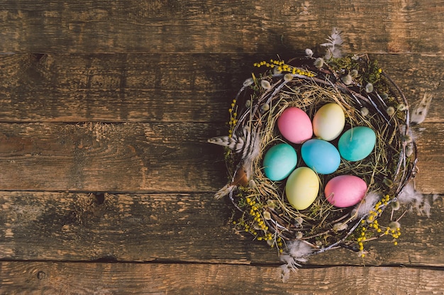 Oeufs de Pâques colorés dans un beau nid. Dans le contexte d'une vieille planche de bois.