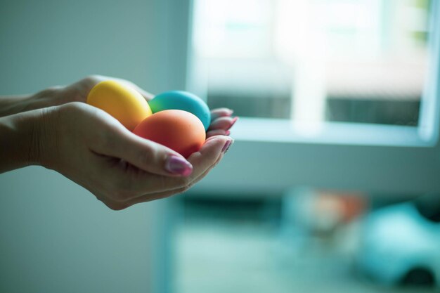 Les oeufs de pâques colorés dans des mains de femme montrent le religieux