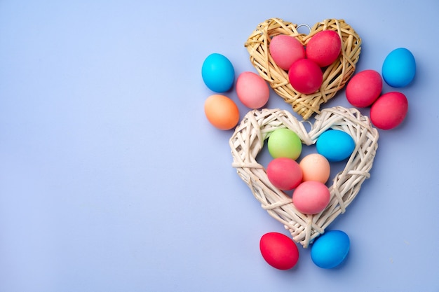 Oeufs de Pâques colorés dans un nid décoratif sur bleu