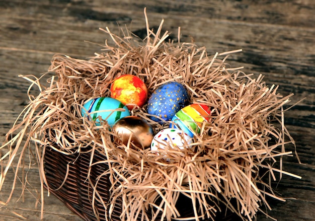 Oeufs de Pâques colorés dans le nid sur fond de bois