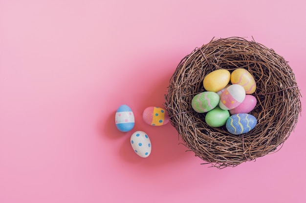 Oeufs de Pâques colorés dans un nid sur fond de couleur pastel rose avec espace.