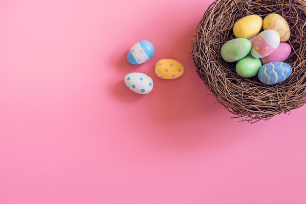 Oeufs de Pâques colorés dans un nid sur fond de couleur pastel rose