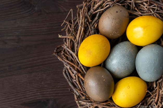 Oeufs de Pâques colorés dans un nid d'oiseau sur une table en bois Vue de dessus Espace de copie