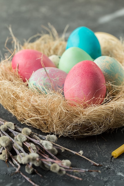 Oeufs de Pâques colorés dans un nid de paille sur une table