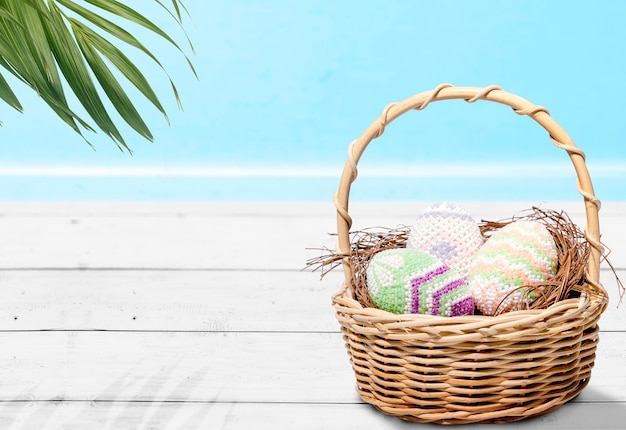 Oeufs de Pâques colorés dans le nid sur un panier en bois sur la table. Joyeuses Pâques