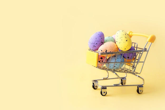 Oeufs de pâques colorés dans le panier sur fond jaune. Espace de copie.