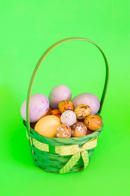 Photo oeufs de pâques colorés dans un panier sur fond vert doux.