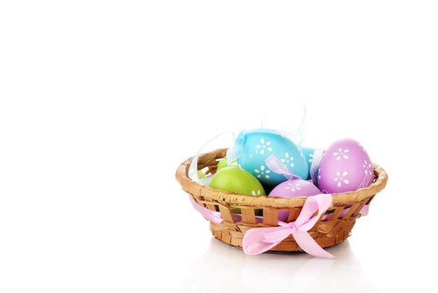 Oeufs de Pâques colorés dans le panier isolé sur blanc