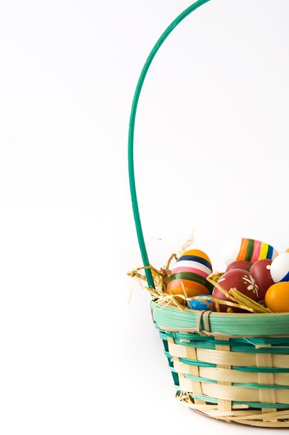 Photo oeufs de pâques colorés dans un panier isolé sur une surface blanche