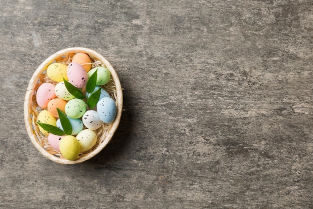 Oeufs de Pâques colorés dans un panier en osier sur fond coloré vue de dessus en gros plan avec espace de copie