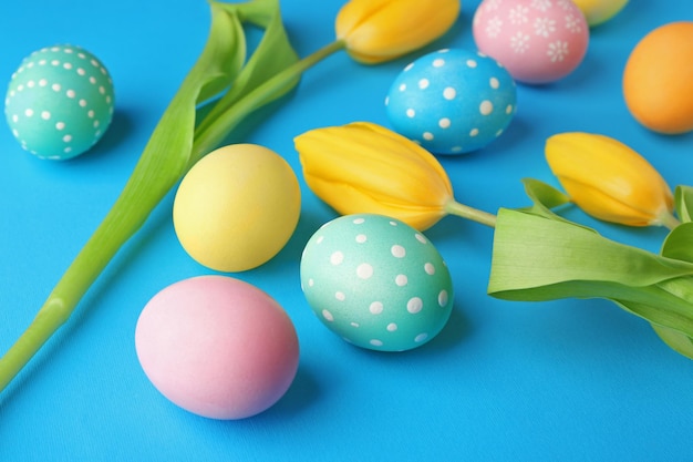 Oeufs de Pâques colorés et fleurs sur fond bleu