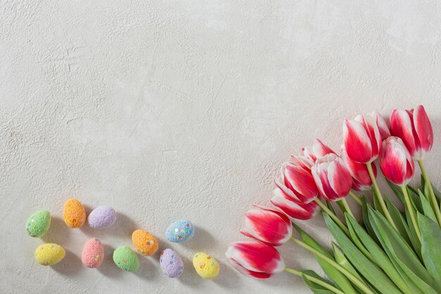 Oeufs de Pâques colorés et fleurs de tulipes sur fond clair à plat avec espace de copie Espace pour le texte