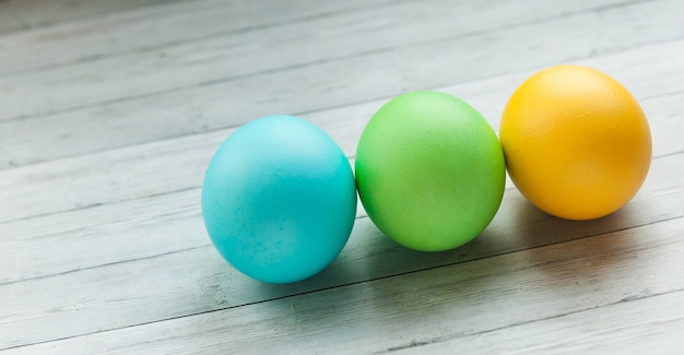 Oeufs de Pâques colorés sur un fond en bois clair.