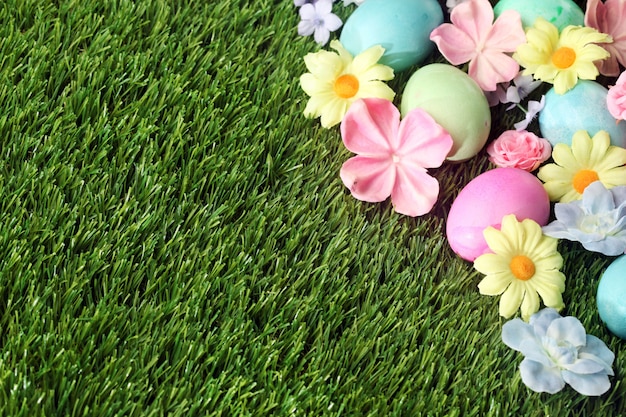 Photo oeufs de pâques colorés sur l'herbe avec fond de fleurs