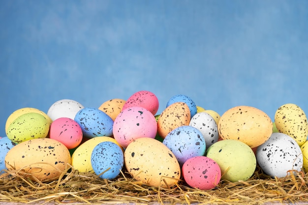 Oeufs de Pâques colorés sur l'herbe sèche sur fond bleu ciel