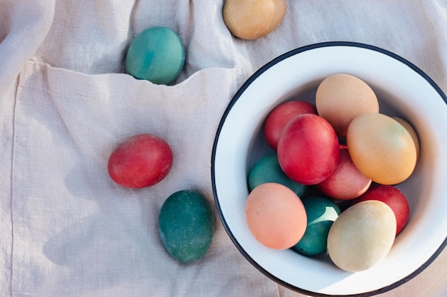 Oeufs de Pâques colorés rustiques dans un bol de fer sur une toile de lin sur l'herbe Concept de vacances de printemps