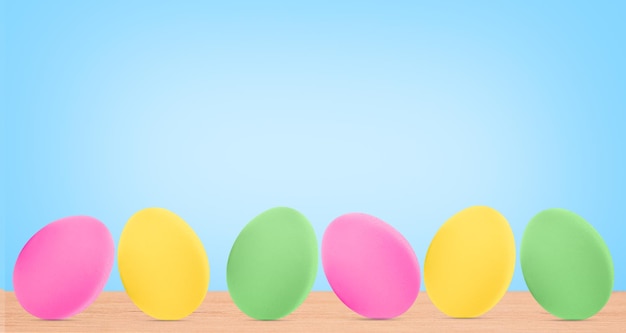 Oeufs de Pâques colorés sur une table en bois sur fond bleu