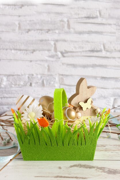 Oeufs de Pâques de couleur dorée et lapin de Pâques dans un panier vert fond de Pâques Copyspace