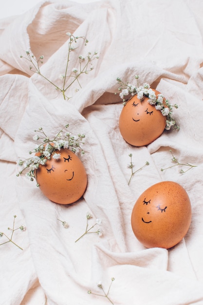 Photo oeufs de pâques avec des couronnes de fleurs décoratives entre textile