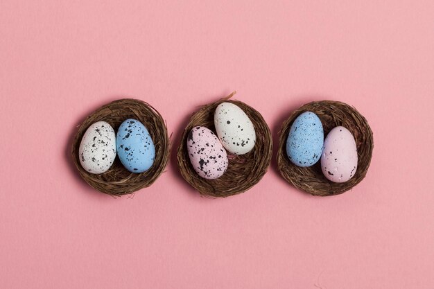 Oeufs de Pâques dans un nid sur fond rose pastel