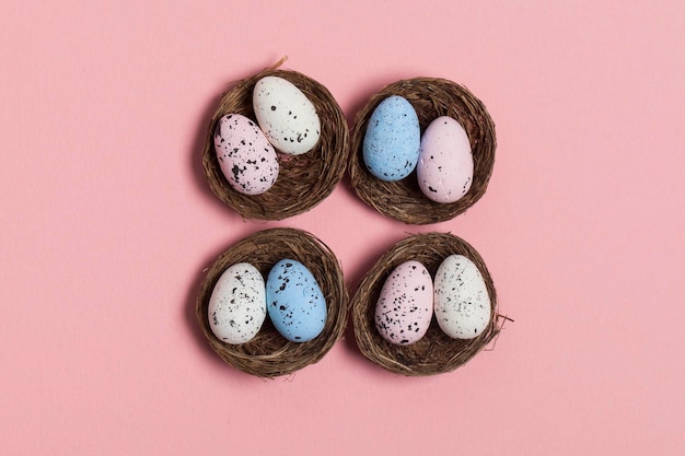 Oeufs de Pâques dans un nid sur fond rose pastel