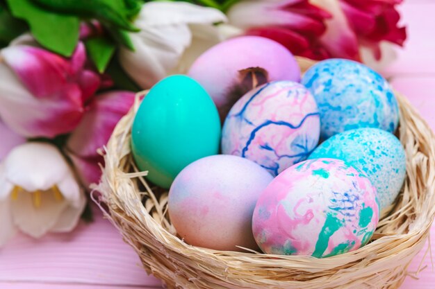 Oeufs de Pâques dans un nid et tulipes sur des planches de bois