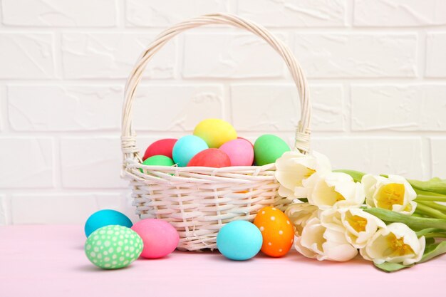 Oeufs de Pâques dans un panier et fleurs sur la table