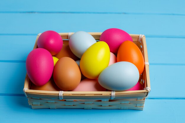 Oeufs de Pâques dans le panier sur le mur en bois bleu