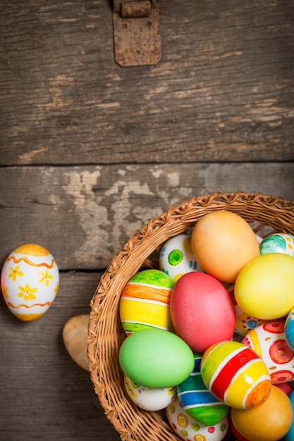 Oeufs de Pâques dans le panier sur des planches en bois