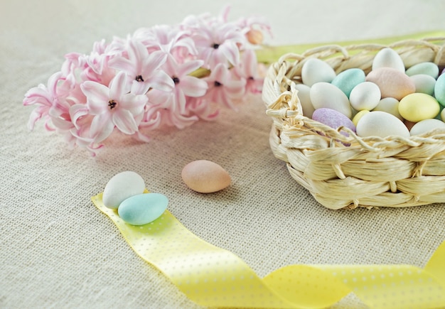 Oeufs de Pâques dans le panier avec ruban jaune et bourgeon frais de jacinthe rose