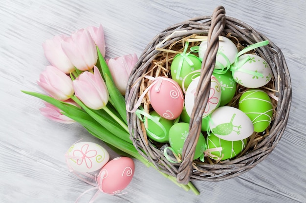 Oeufs de pâques dans le panier et les tulipes