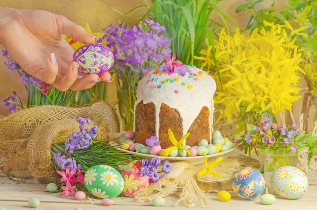 Oeufs de Pâques et décoration de Pâques sur le fond en bois Mains tenant un oeuf de Pâques peint Oeufs de Pâques colorés dans la main féminine