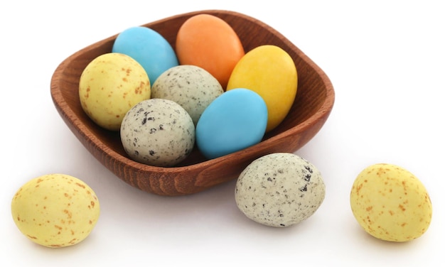 Oeufs de Pâques décorés dans un bol en bois sur fond blanc