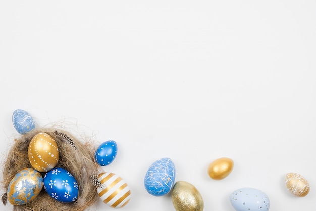 Oeufs de Pâques décorés d'or dans un nid isolé sur une surface blanche. Concept de Pâques minimal.