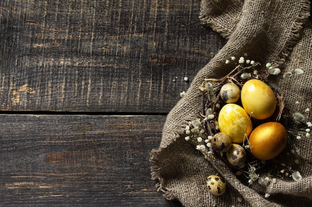 Oeufs de pâques dorés dans le nid et la décoration de pâques sur la table en bois Vue de dessus mise à plat