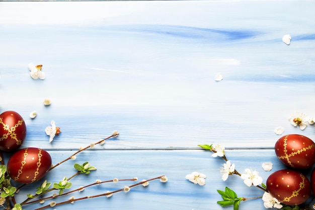 Oeufs de Pâques et fleurs blanches printanières et branches de saule sur fond de bois bleu de Pâques avec espace de copie