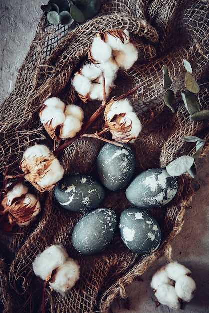 Oeufs de Pâques et fleurs de coton sur pierre grise.